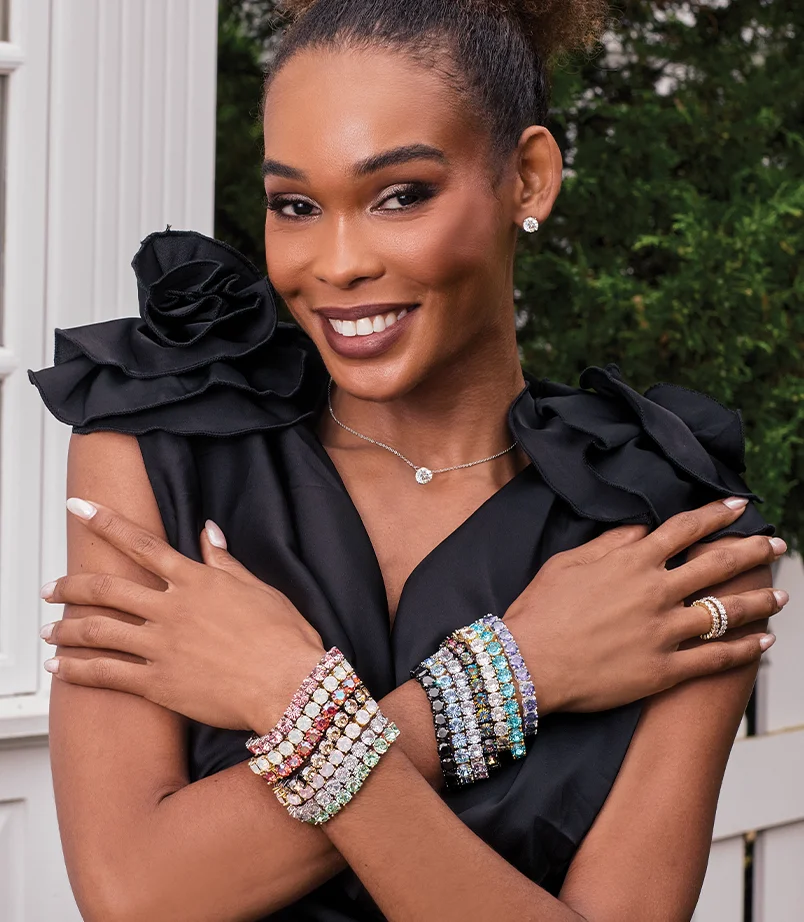 Model wearing Gold heart jewelry leaning against the wall